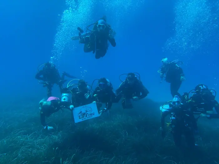 Grupo de buceadores posa con la bandera de La Frau sobre la posidonia