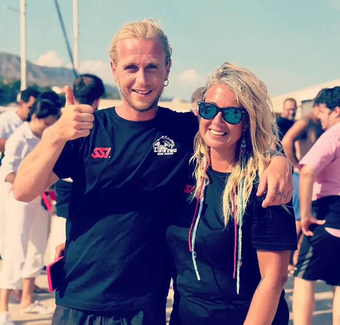 Tom y Glenda, sonrientes, con la camiseta de La Frau en el puerto